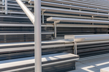 Close-Up of empty metal stadium bleacher seats along aisle with steps and railing.
