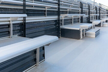 Empty metal outdoor stadium accessible bleacher seats with companion seats at front aisle.
