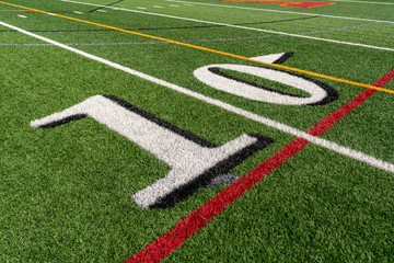Synthetic turf  slanted football 10 yard line in white with black number shadow along with red...