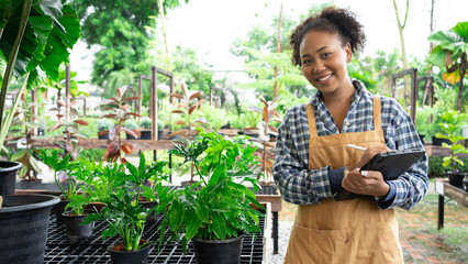 Portrait of beautiful women owner standing in own tree shop and smiling. African American females business partners working garden store. Business concept.Tablet quality control.Clip board.