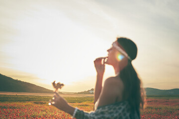 A woman eating strawberries at sunset in a field of poppies. Selective focus. Blurred image. Front view.