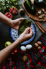 mexican woman hands peeling poblano chillies pepper for cooking chiles en nogada traditional dish...
