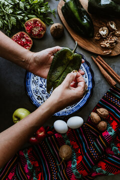 mexican woman hands peeling poblano chillies pepper for cooking chiles en nogada traditional dish in Puebla Mexico	
