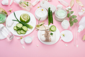 Face and body care products assortment on pink background.