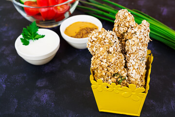 Chicken fillet in oat flakes on dark background
