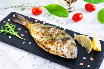 Grilled dorado fish on white background. Roasted seafish with spice and herbs