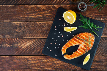 Grilled salmon fish on stone board. Salt atlantic salmon fried on grill with lemon. Top view