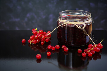 Jar with jam of red currant on dark background