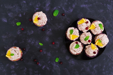 Lemon cupcakes with cherry cream. Cranberry, mint leaves. Food on a dark background. Top view