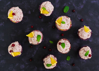 Lemon cupcakes with cherry cream. Cranberry, mint leaves. Food on a dark background. Top view
