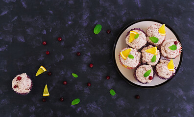 Lemon cupcakes with cherry cream. Cranberry, mint leaves. Food on a dark background. Top view