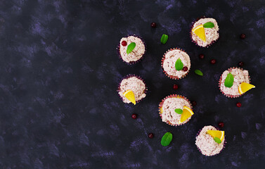 Lemon cupcakes with cherry cream. Cranberry, mint leaves. Food on a dark background. Top view
