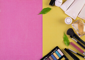 Makeup cosmetics on pink-yellow background. Top view. Copy space