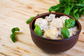 Meatballs with cream and mushrooms on wooden background