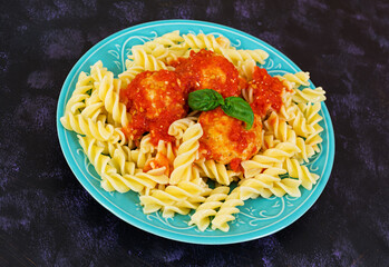 Meatballs with fusilli on dark background.