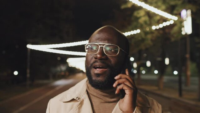 Young adult African American man having phone call with girlfriend while heading home after long work day late in evening or at night