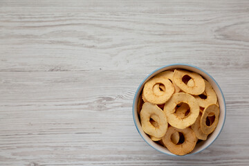 Homemade apple chips in a bowl on a white wooden background, top view. Flat lay, overhead, from above. Space for text.