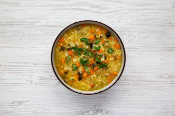 Homemade fresh lemon rice soup in a bowl on a white wooden background, top view. Flat lay, overhead, from above.