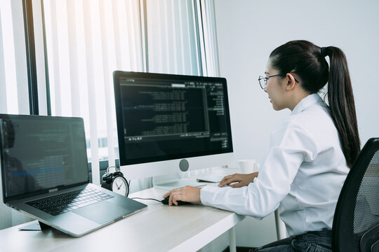 Woman asian software developers are analyzing together about the code written into the program on the computer in office room.