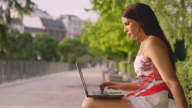 Trans woman using a laptop outdoors