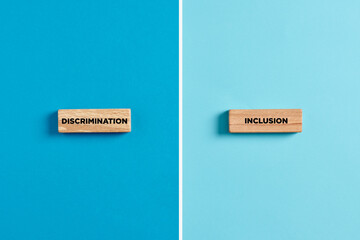 The words discrimination and inclusion on wooden blocks. Dilemma or choice between discrimination or inclusion