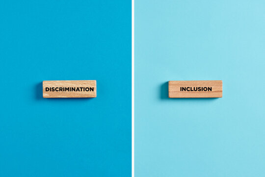 The words discrimination and inclusion on wooden blocks. Dilemma or choice between discrimination or inclusion