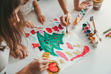 children with their mother draw a drawing with paints and brushes, gouache, an elegant Christmas...