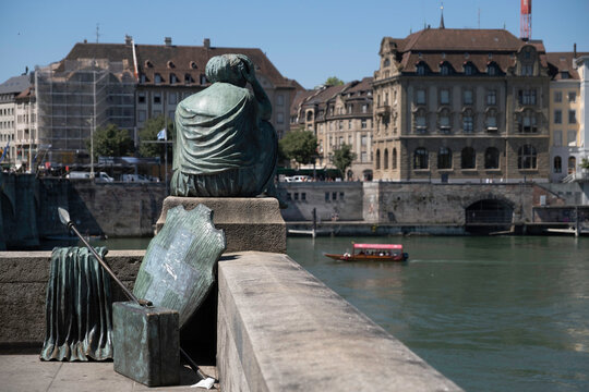 BASEL, SWITZERLAND - JULY 10 2022: Helvetia bronze statue in gown, with a spear and a shield emblazoned with the Swiss flag looking out over the river Rhine in Basel, Switzerland