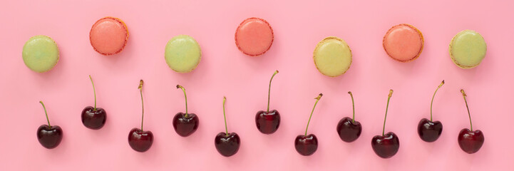 Red cherries and macarons on pink banner
