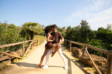 Handsome young man and woman dancing bachata and salsa in the park. The couple dance passionately...