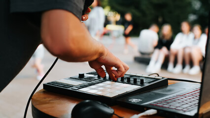Close-up of an unrecognizable musician beatmaker playing hip hop music on a drum midi controller at...