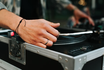Close-up of DJ mixing vinyl records on turntable at street music festival in evening. Selective...