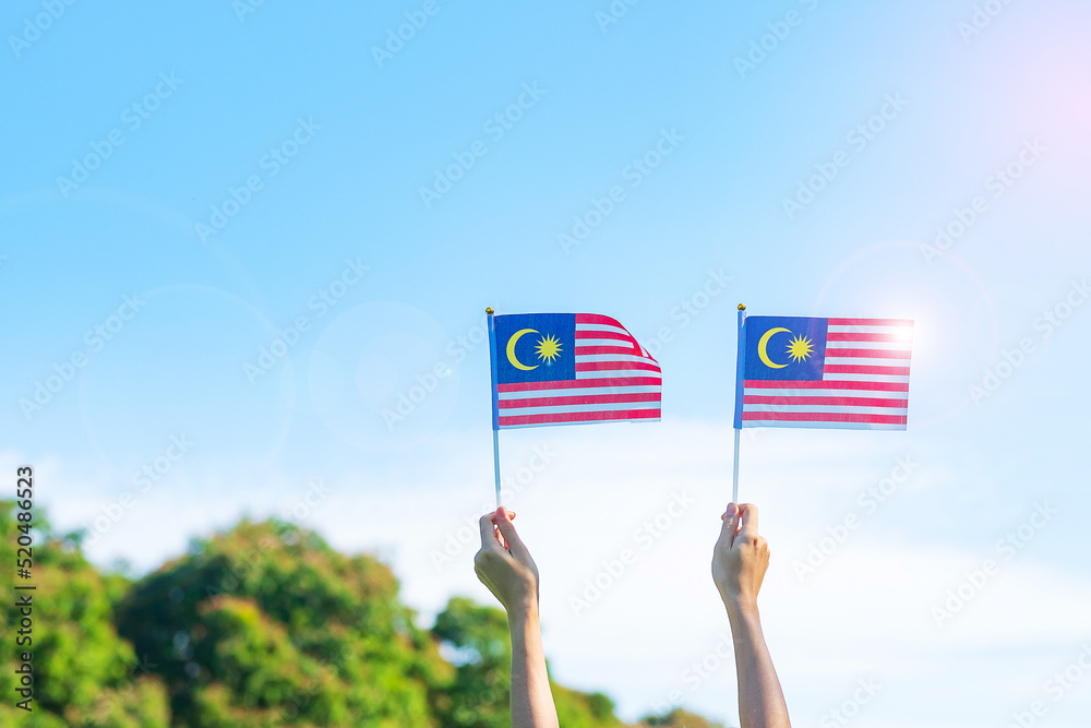 Wall mural hand holding Malaysia flag on blue sky background. September Malaysia national day and August Independence day