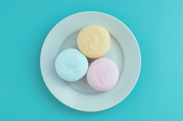 Marshmallows on  white plate. Turquoise background. View from above.