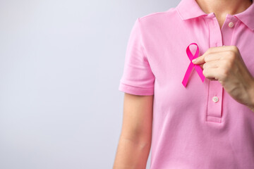 Pink October Breast Cancer Awareness month, woman hand hold pink Ribbon and wear shirt for support people life and illness. National cancer survivors month, Mother and World cancer day concept - obrazy, fototapety, plakaty