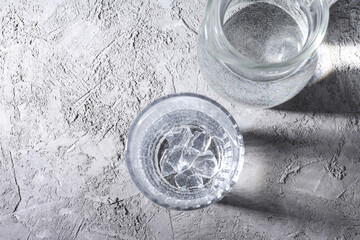Jug and glass of water on gray textured background