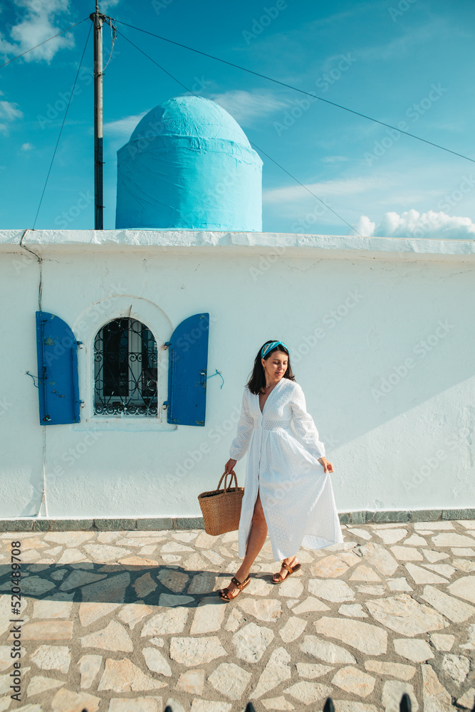 Wall mural beautiful woman in white dress near old greece church