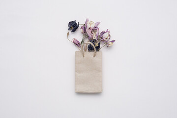 Paper shopping bag with dried flowers bouquet. Autumn gift sales concept.
