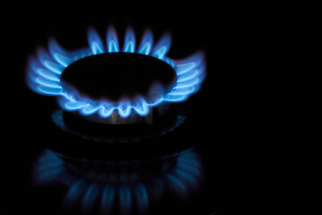 Flaming gas burner on household kitchen stove in the darkness
