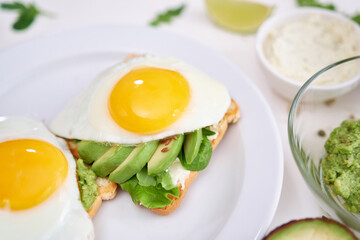 healthy breakfast or snack - sliced avocado and fried egg on toasted bread 