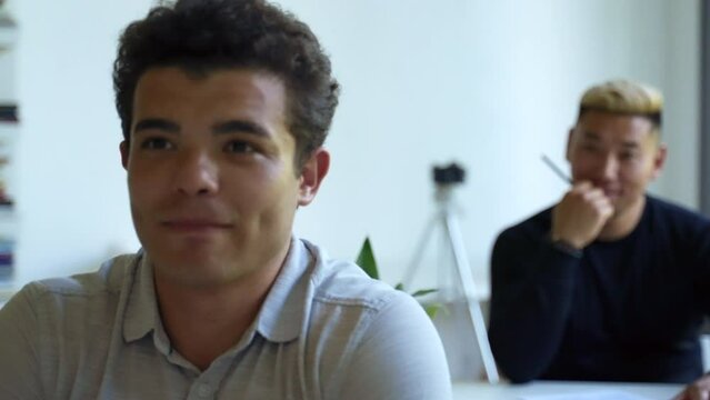 Hardworking employees learn new skills at business conference. Focus changes from blond dyed guy with pen in hand to man with smile on face closeup