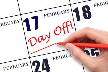17th day of February. Hand writing text DAY OFF and drawing a line on calendar date 17 February. Vacation planning concept. Winter month, day of the year concept.