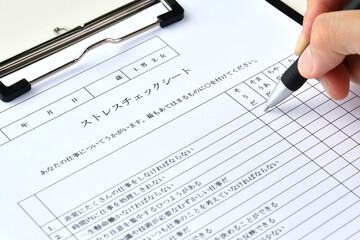 ストレスチェックシートに記入するビジネスマンの手元