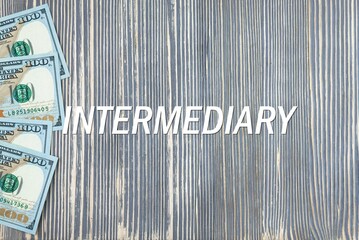 INTERMEDIARY - word (text) on wooden background, money, dollars. Business concept (copy space).