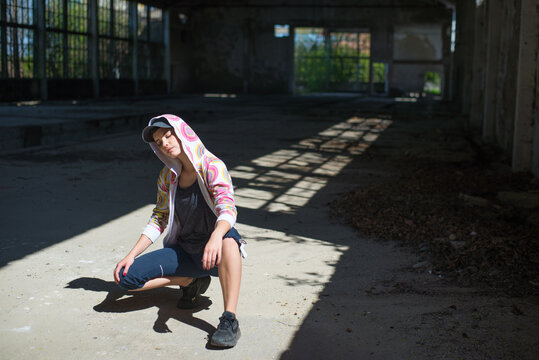 Young woman street dancer dancing and jumping in abandoned building on a sunny summer day