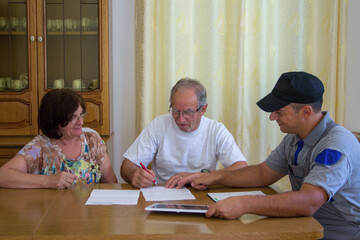 Image of a handyman plumber presenting a quote for the work to be done to an elderly couple.	