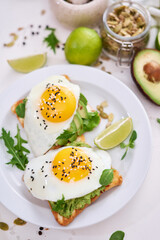 healthy breakfast or snack - sliced avocado and fried egg on toasted bread 