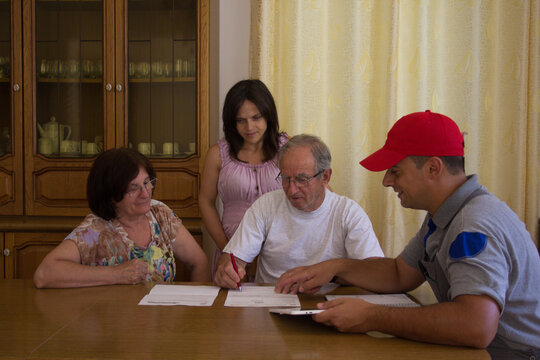 Image of an elderly couple with their daughter signing a contract with a handyman for the renovation of the house. Family talking to a worker for housework