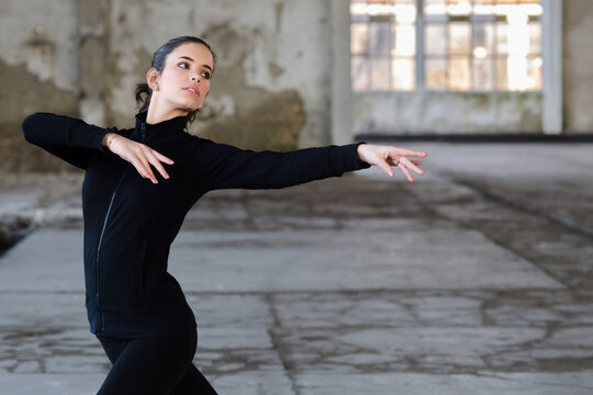 Young ballerina stretching and dancing in abandoned building