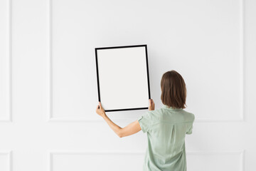 Woman hold blank picture frame mockup on white wall, Artwork mock-up in minimal interior design, Minimal photographer artist concept.